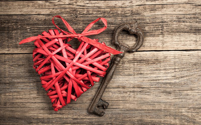 Red wicker heart and vintage key on wooden background